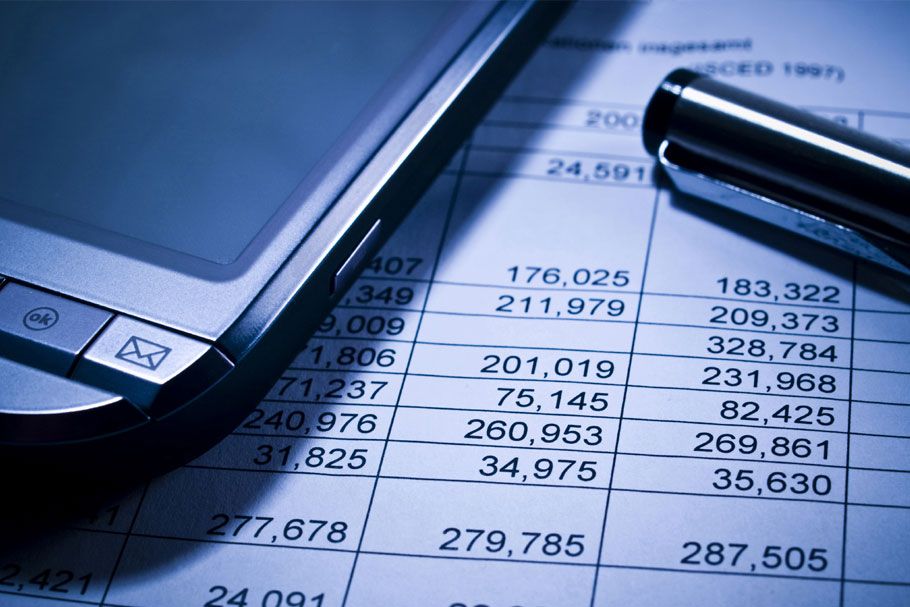 A close-up of a smartphone, a metallic pen, and printed financial charts.