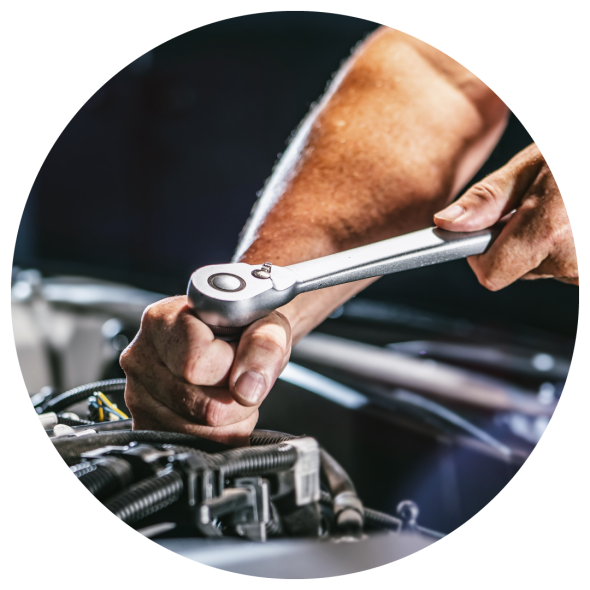 An image of a mechanic's hands using a ratchet wrench to make an adjustment on a car engine.