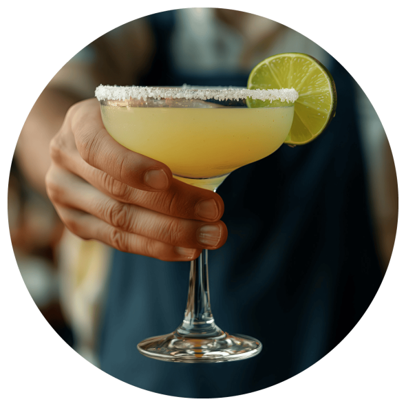 A male bartender presenting a freshly made margarita with a lime garnish.