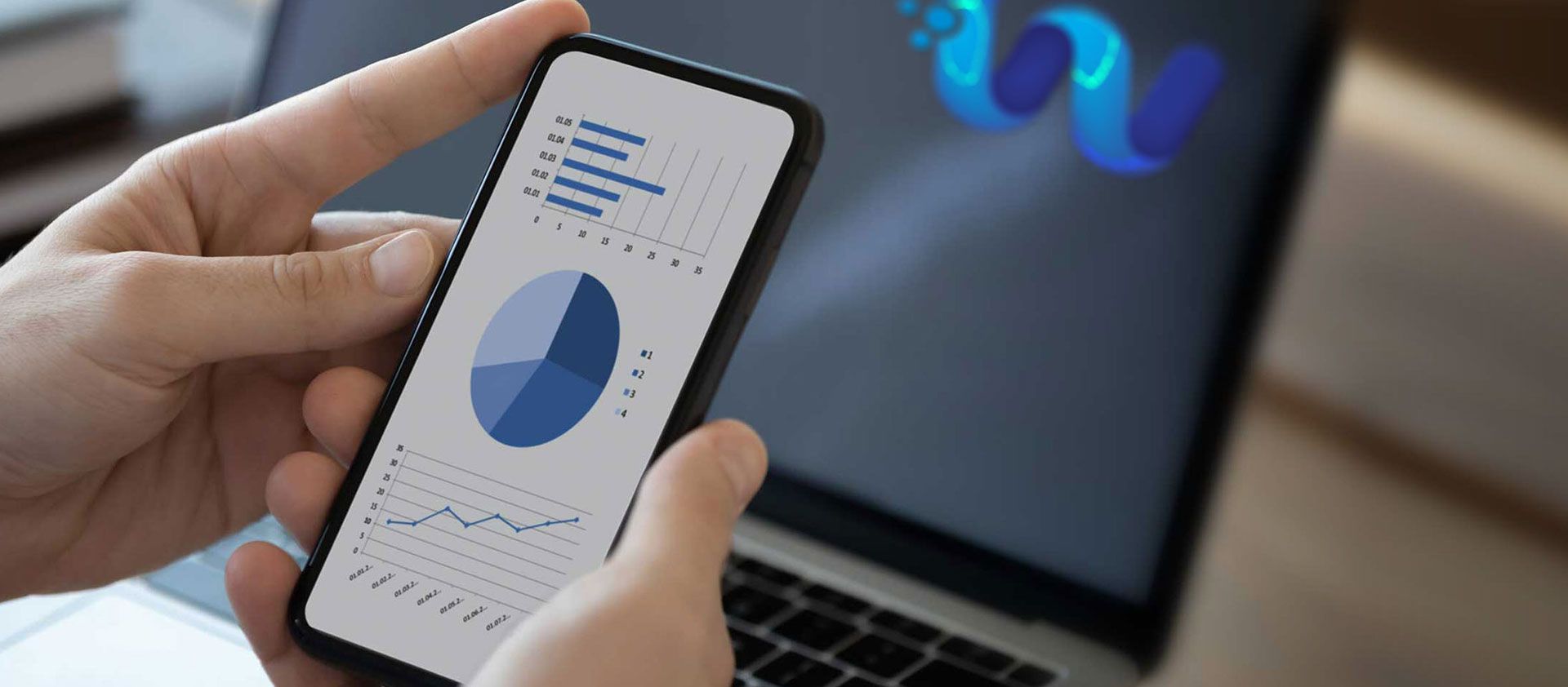 Close-up of a person's hands holding a phone displaying financial data, with a laptop in the background showing the 'We Do Books' logo on the screen.